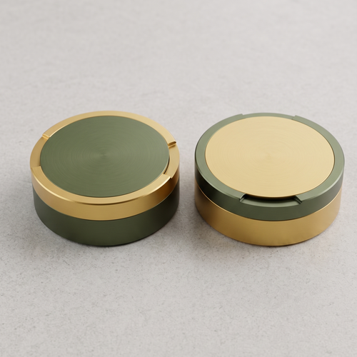 En parbild med två runda metalldosor i storlek large, sida vid sida på en ljusgrå yta. En dosa är olivgrön med guldringar, den andra är guld med en olivgrön ring. 